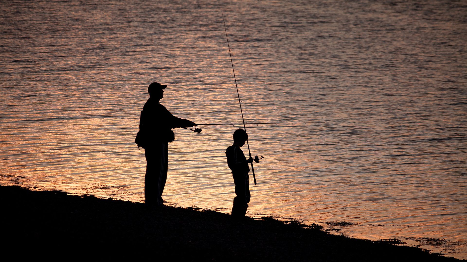Father and son fishing on a lake shore