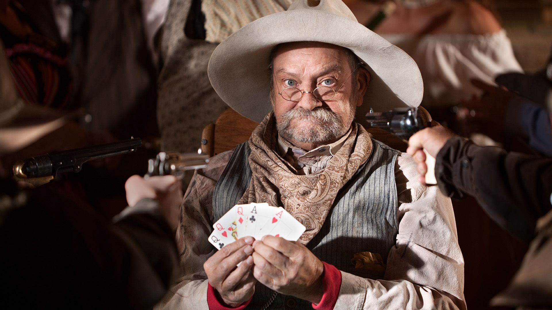 Gambler with cards and players guns pointed at him